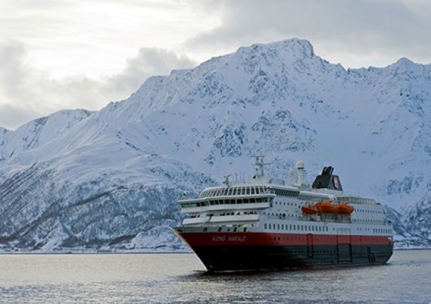 Ein Postschiff fährt auf dem Wasser vor der malerischen Kulisse Norwegens während einer Kreuzfahrt.