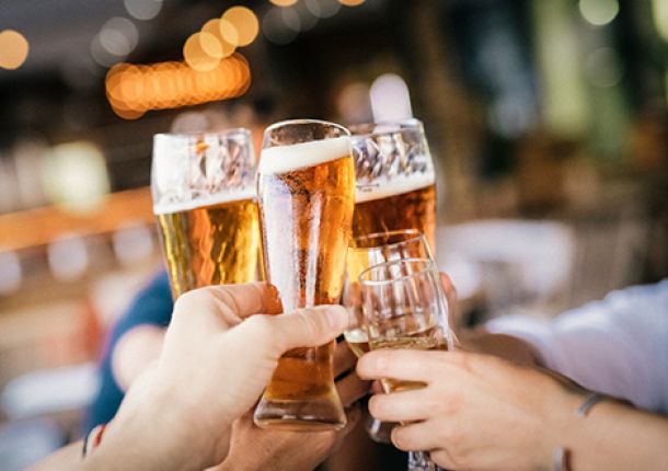 Mehrere Personen stoßen mit vollgefüllten Biergläsern an, um gemeinsam zu feiern.