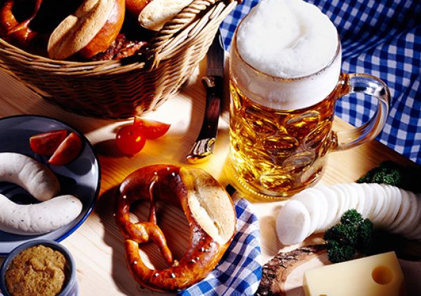 Tisch gedeckt mit einem Maß Bier, einer Brezel und Weißwürsteln.
