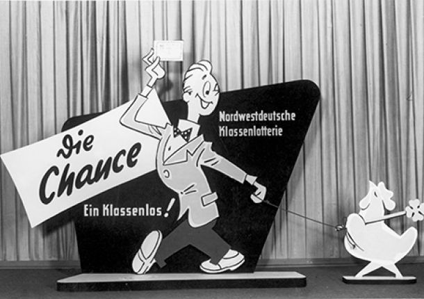 Pappschild zur Nordwestdeutschen Klassenlotterie, mit einer männlichen Figur, die ein Los in der Hand hält.