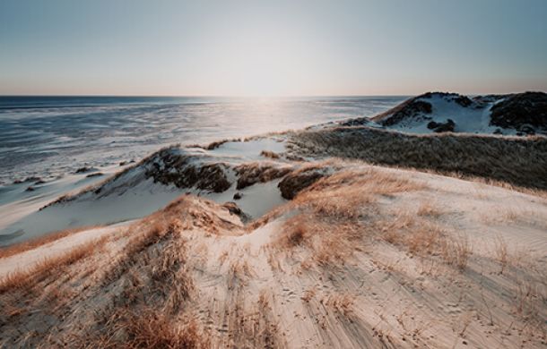 Ein malerischer Strand am Meer, mit sanften Wellen und Hügeln im Hintergrund.