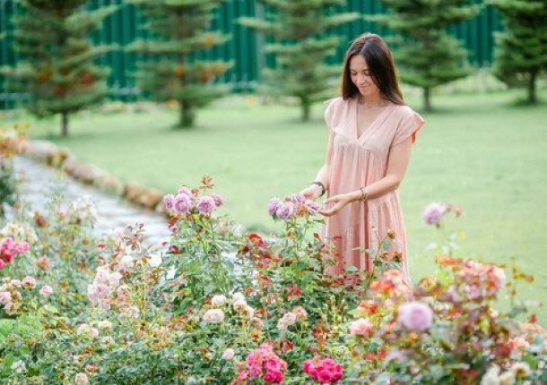 Junges Mädchen in einem Blumengarten zwischen wunderschönen Rosen.