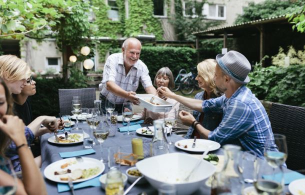 Familie sitzt an einem Tisch und genießt eine Mahlzeit, während sie gemeinsam am Grillen sind.