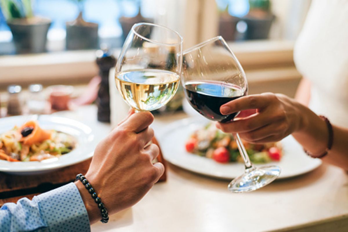 Junges Paar stößt fröhlich mit zwei Gläsern Wein an und feiert gemeinsam.