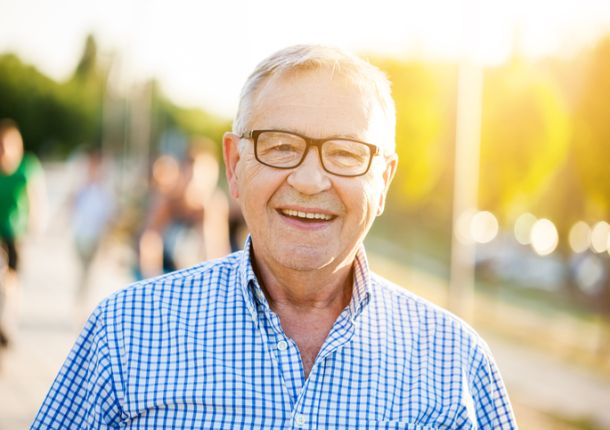 Outdoor-Portrait eines glücklichen älteren Mannes, der in die Kamera schaut und lächelt.