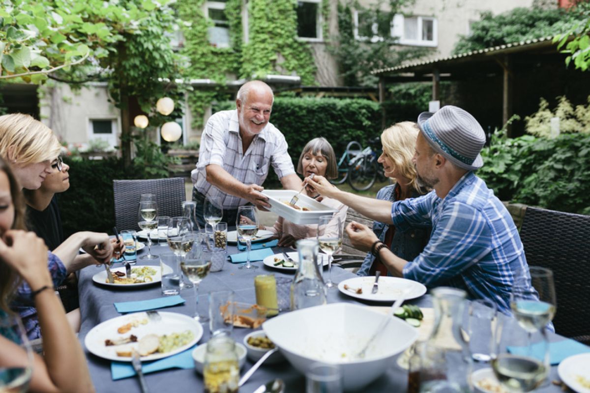 Familie sitzt an einem Tisch und genießt eine Mahlzeit, während sie gemeinsam am Grillen sind.