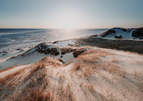 Ein malerischer Strand am Meer, mit sanften Wellen und Hügeln im Hintergrund.