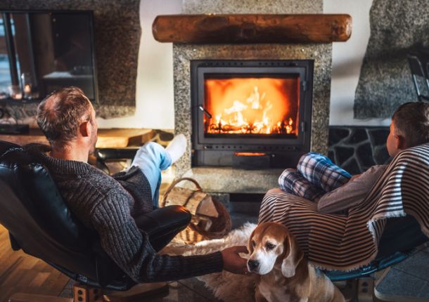 Vater und Sohn sitzen in bequemen Sesseln in ihrem Landhaus nahe dem Kamin und genießen die warme Atmosphäre.