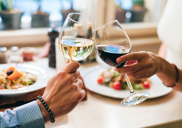 Junges Paar stößt fröhlich mit zwei Gläsern Wein an und feiert gemeinsam.